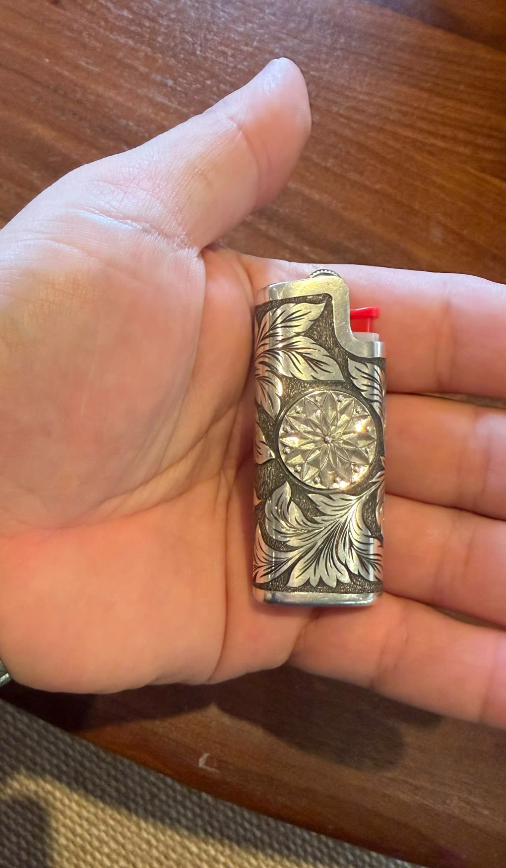 Silver lighter case engraved with leaves and a faceted medallion
